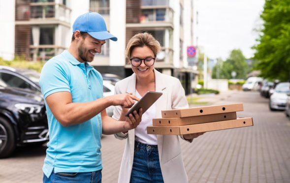 Delivery man wearing blue uniform delivers pizza to a woman clie